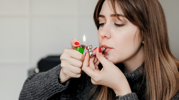 young adult woman smoking legal marijuana from pipe at home